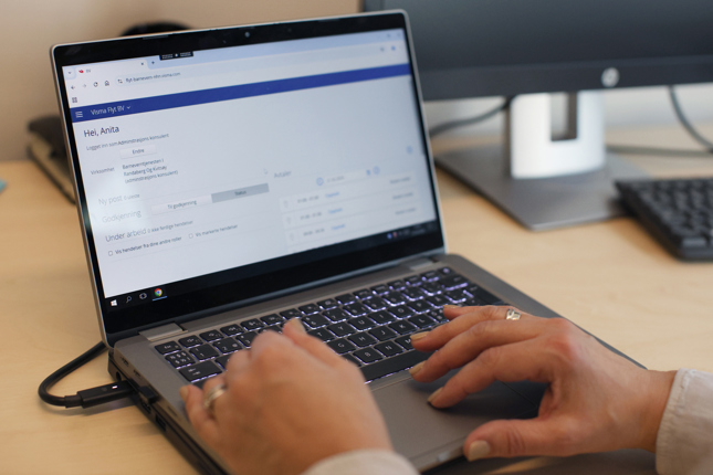 Hender som skriver på tastaturet på en pc, og viser det nye barnevernsystemet på skjermen