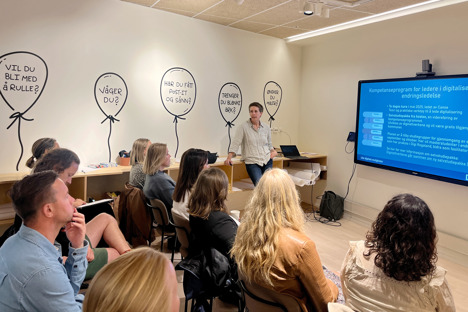 Christine Sandvold presenterer foran storskjermen med folk som ser på