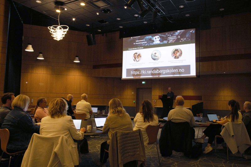 Odin Nøsen snakker foran, til folkene rundt bordene i salen.