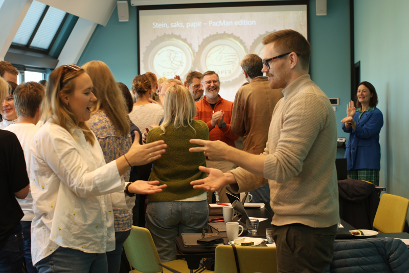Personer som utfører en lek, hvor de står mot hverandre og løfter hendene.