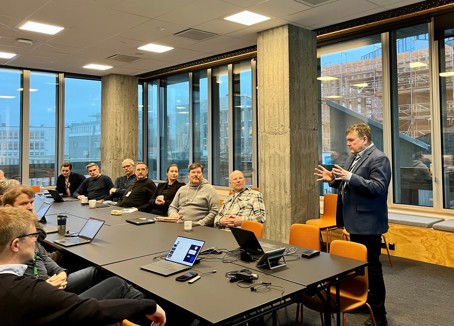 Bildet viser Rune Hauge som snakker til en rekke folk som sitter rundt møtebordet.