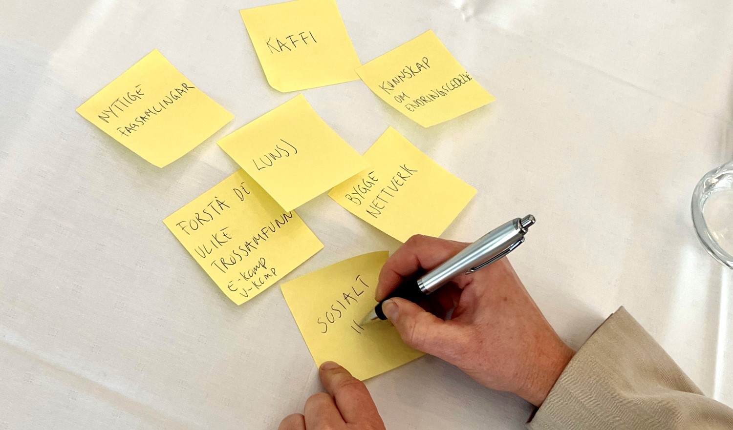 Bildet viser en hånd som skriver på postitlapper.