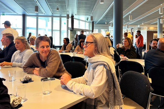 Bildet viser Christine Sandvold som sitter på et bord sammen men andre konferansedeltakere.
